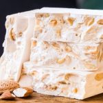 Homemade sticky nougat with crunchy hazelnuts on baking paper, ready to be sliced
